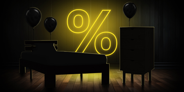  Černá postel a komoda s černými balónky před jasně žlutým znakem procenta na tmavé dřevěné podlaze.